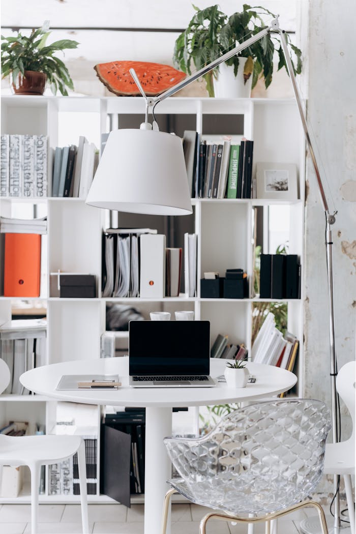 A stylish and minimalist home office setup featuring a laptop, books, and a modern lamp.