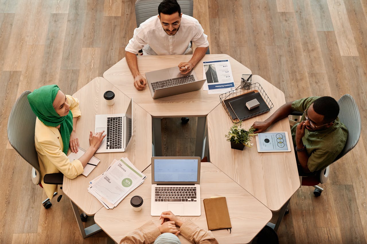 Top view of diverse coworkers collaborating at a modern office table.